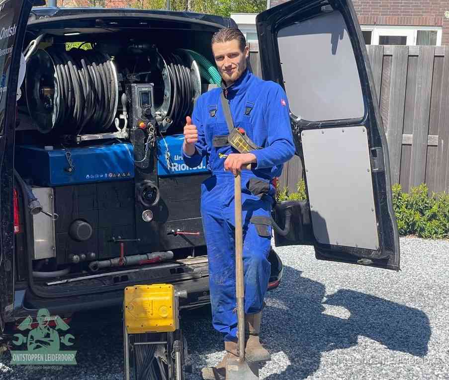 Een tevreden monteur met opgestoken duim naast de bestelbus, slim en snel ingrijpen bespaart geld bij een verstopping in Leiderdorp