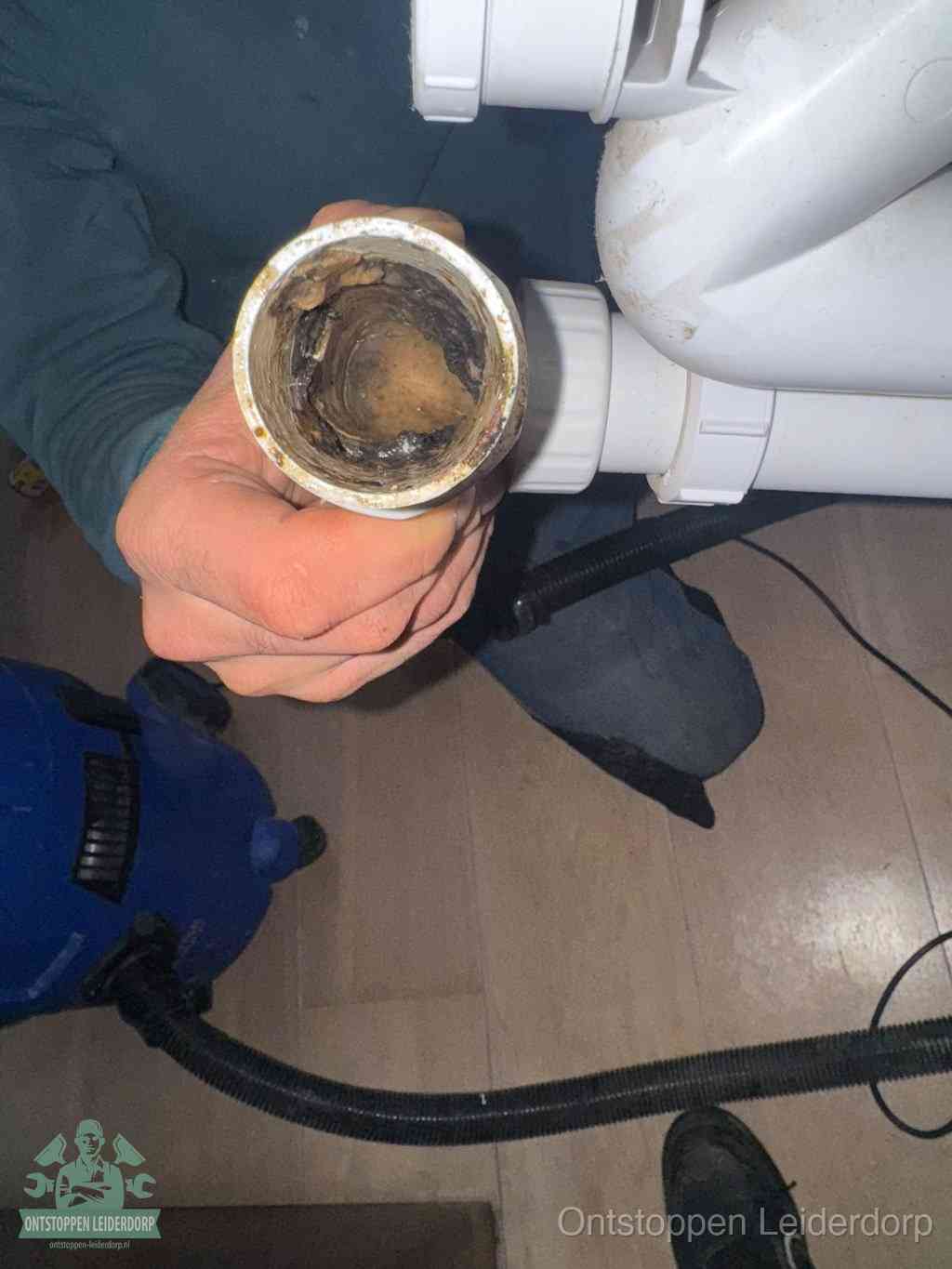 Een losgekoppeld PVC-afvoerbuisstuk dat van binnen volledig is dichtgeslibd met vet en vuil, de meest voorkomende oorzaak van verstoppingen in Leiderdorp