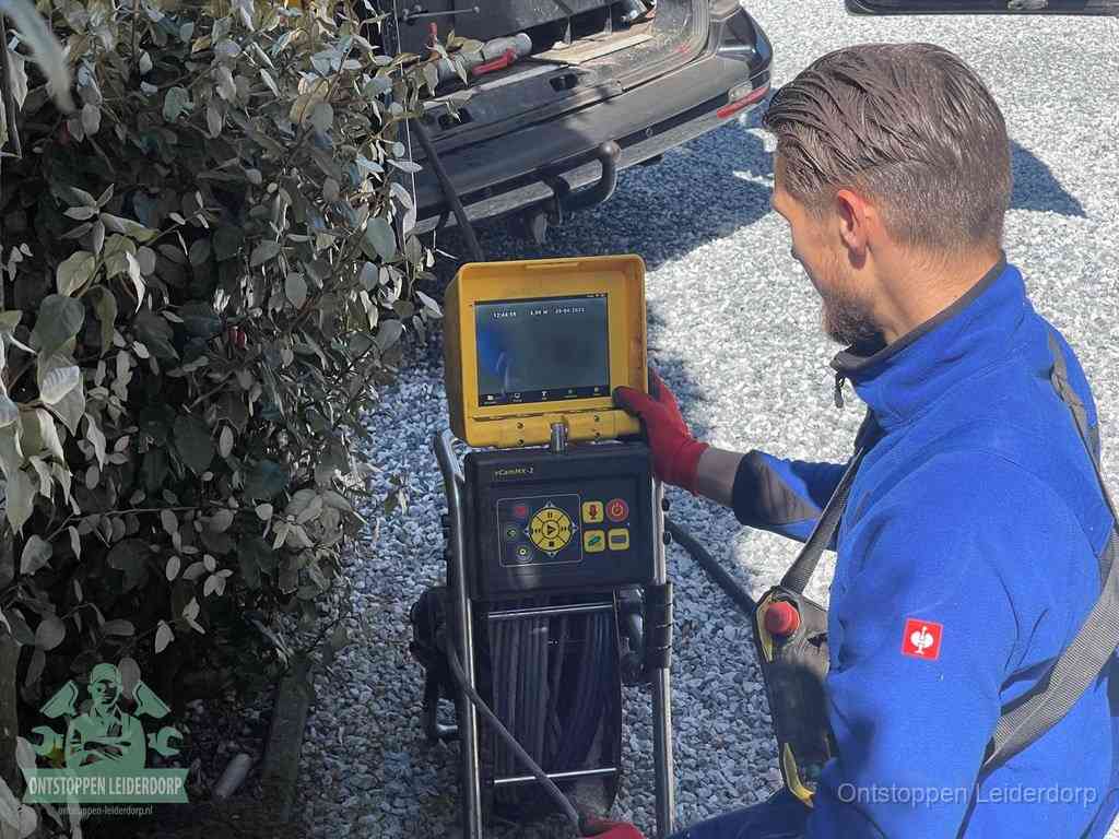 Een monteur bedient een rioolinspectiecamera met monitor en haspel om de verstopping in beeld te brengen in Leiderdorp