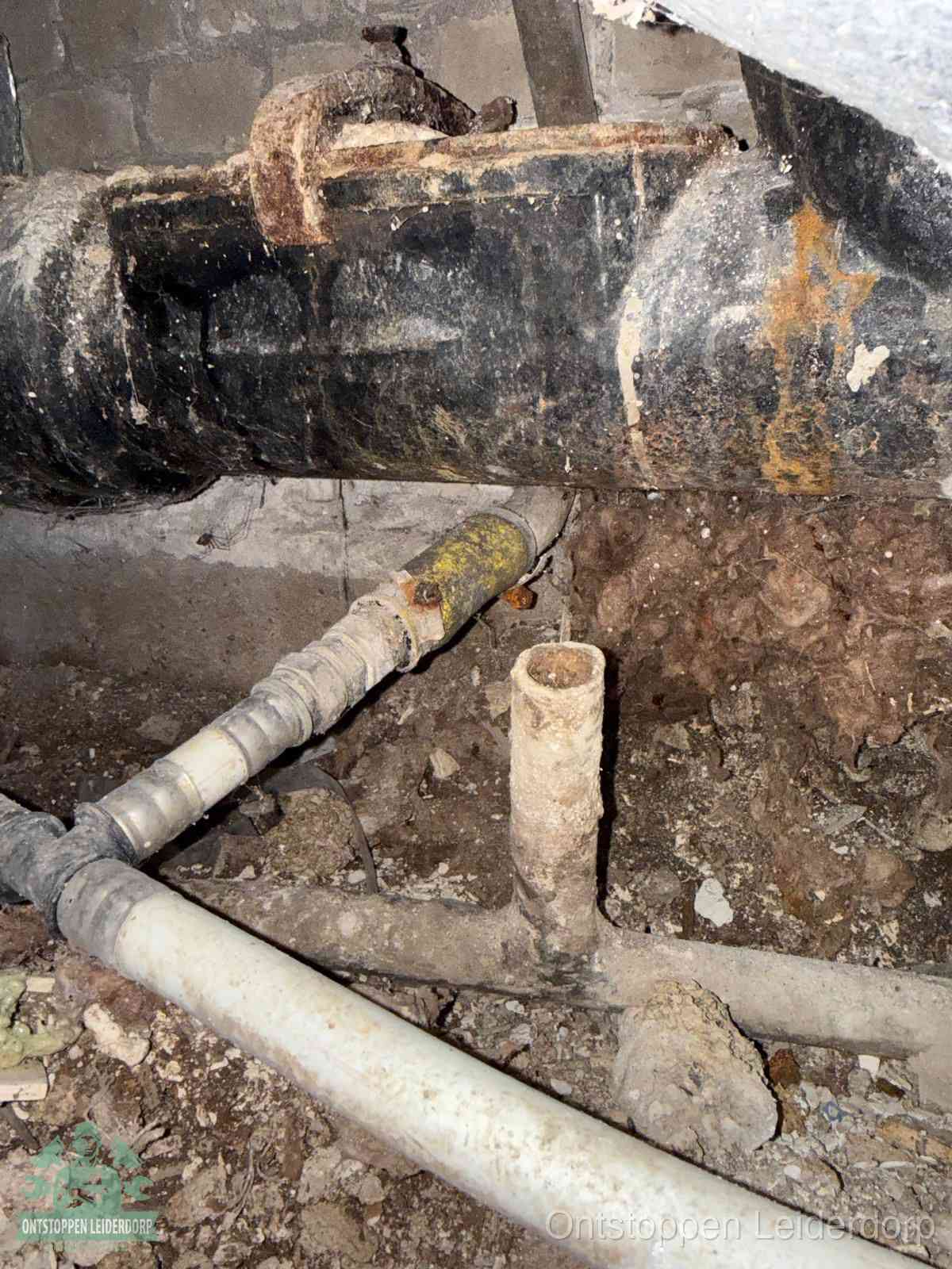 Een oude hoofdrioolbuis met roest- en kalkaanslag in een kruipruimte, oorzaak van terugkerende structurele rioolproblemen in Leiderdorp